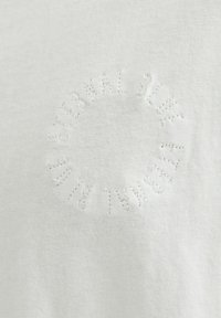 White cotton t-shirt featuring embossed circular text "ETERNAL BLUE" in a raised pattern, creating a textured detail on the fabric.