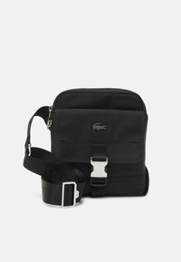 Borsa a tracolla nera in tessuto con forma rettangolare, dotata di patta frontale, dettagli in argento e tracolla regolabile con brand.
