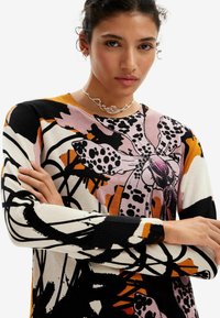 Strickpullover mit floralen Motiv in Rosa, Schwarz, Orange und Creme. Lange Ärmel, runder Halsausschnitt und gerippte Bündchen.