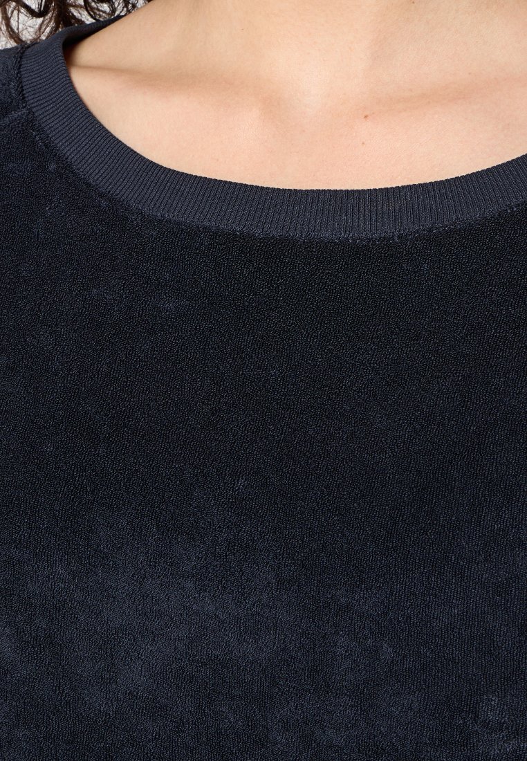 Schwarzer Sweatshirt mit rundem Halsausschnitt und geripptem Saum, aus weichem, strukturiertem Stoff gefertigt. Die Oberfläche wirkt leicht abgetragen.