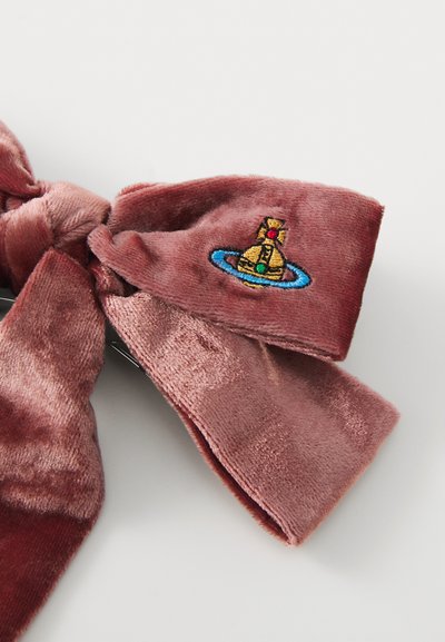 Samta matu aksesuārs putekļrozā krāsā ar lielu loku, kuram ir daudzkrāsains izšuvums ar zelta zvanu un zilu gredzenu.