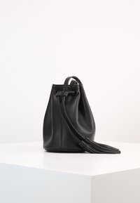 Borsa a secchiello in pelle nera con forma arrotondata, chiusura a coulisse e dettaglio con nappina. Texture liscia con design minimalista.