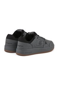 Zapatillas deportivas grises con un upper sintético liso, que presentan acentos negros, detalles de perforación y una suela de goma con un tread texturizado.