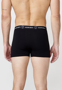 Fekete boxer alsónadrág KOROSHI logós derékkal. Rugalmas anyagból készült, testhezálló kialakítással és térd középig érő hosszal.