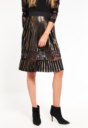 Fållad svart och guldram kjol med metalliska ränder, en spetsdetalj och ett svart elastiskt midjeband. Matchad med svarta ankelstövlar.