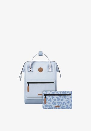 Heller blauer Rucksack mit einem Leder-Logo-Patch, Reißverschluss-Schlüssen und zwei Seitentaschen. Begleitet von einem passenden, gemusterten Täschchen.