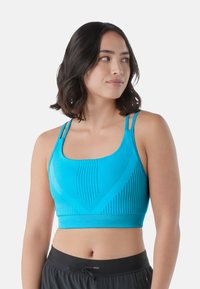 Sujetador deportivo azul brillante con un diseño texturizado que presenta rayas verticales, un escote redondeado y tirantes finos ajustables.