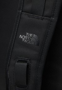 Mustmust kottide must rihm tekstuuriga pinnaga. Selles on läikiv must logo "THE NORTH FACE" ja tugevdatud kinnituspink.