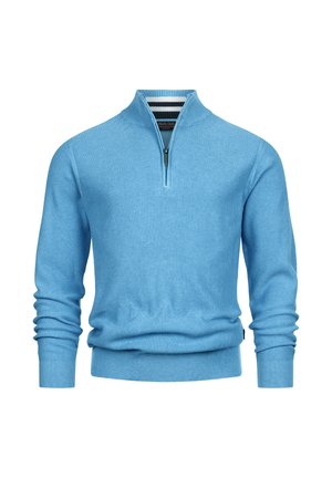 Lys blå pullover med en lynlås krave, ribbet struktur og tætsiddende ærmer. Har et subtilt strikmønster og en sort stribe ved halsudskæringen.