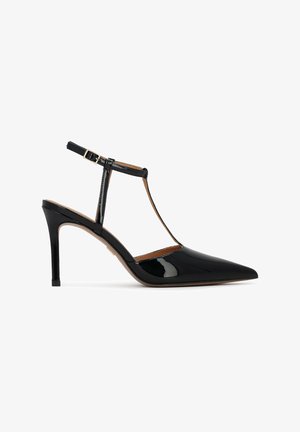 Mustast läikivast nahast kontsaga slingback-king, millel on terav ninaosa, T-tala disain ja õhuke pahkluu rihm, mis kinnitub kuldse pandlaga.