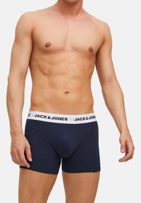 Marineblaue Boxer-Shorts aus dehnbarem Stoff, mit einem weißen elastischen Bund, der auf der Vorderseite mit schwarzer "JACK & JONES"-Schrift versehen ist.