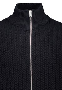 Schwarzer gestrickter Pullover mit hohem Kragen und vollem Reißverschluss, der ein strukturiertes Zickzackmuster im gesamten Stoff aufweist.