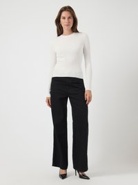 Baltas, raukšlėtas, ilgomis rankovėmis marškinėliai, juodos plačios kelnės ir blizgantys juodi kulniukai. Lygi tekstūra, prigludęs dizainas, kontrastinga spalva.