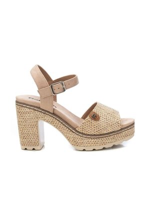 Sandalia beige para mujer con tacón alto y puntera abierta, textura tejida, tira en el tobillo con hebilla plateada y tacón grueso sobre fondo blanco.