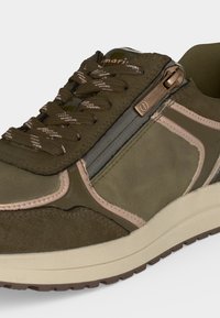 Baskets vert olive avec des accents en daim beige, lacets à motifs, semelle beige et une fermeture éclair fonctionnelle en bronze sur le côté pour un accès facile.