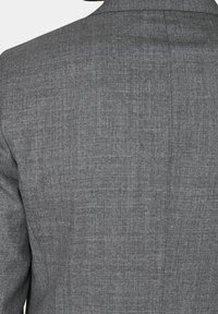 Giacca da smoking grigia con tessuto testurizzato, dotata di rever a punta e due spacchi posteriori, che mostra un design pulito e su misura.