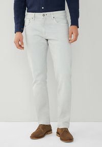 Jeans de color gris claro con corte recto, fabricados en denim. Cuentan con cinco bolsillos, cierre de botón y están combinados con zapatos de ante marrón.