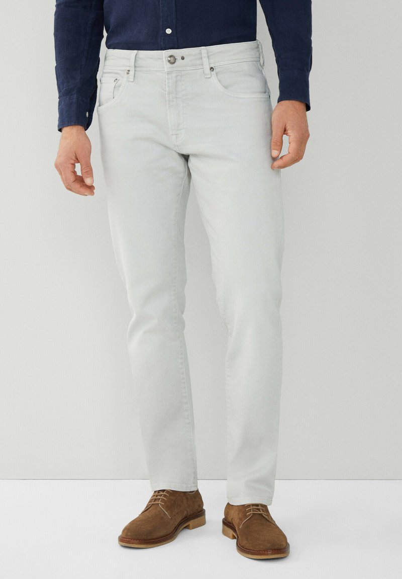 Jeans de color gris claro con corte recto, fabricados en denim. Cuentan con cinco bolsillos, cierre de botón y están combinados con zapatos de ante marrón.