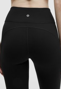 Hochgeschnittene schwarze Leggings aus einem glatten, dehnbaren Stoff. Verfügt über ein nahtloses Design mit einem kleinen Logo auf der Rückseite.