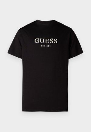 Zwarte T-shirt van katoen, met geborduurde witte tekst "GUESS EST. 1981" op de voorkant. Korte mouwen en een klassiek ronde hals ontwerp.
