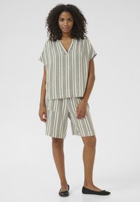 Ensemble top et short léger rayé en blanc cassé et noir. Le haut a un col en V et des manches courtes ; le short a des poches latérales.