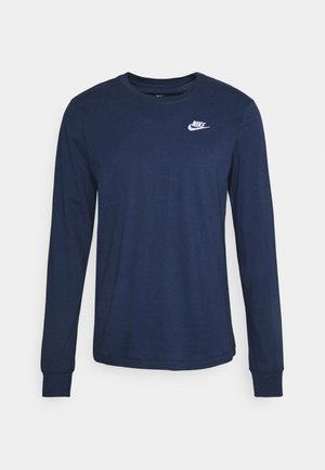 Lahti pitkähihaisella t-paidalla, joka on valmistettu pehmeästä puuvillasta. Paidassa on pyöreä pääntie, istuvat hihat ja valkoinen Nike-logo vasemmassa ylärinnassa.