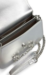Borsa in ecopelle argentata con tracolla a catena, chiusura a scatto e decorazioni in cristallo. L'interno presenta più scomparti.