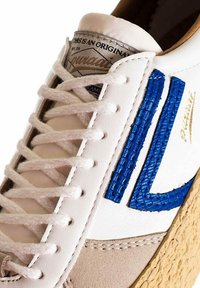 Sneaker bianca in pelle con accenti testurizzati blu, pannello in suede grigio e suola in gomma beige. Presenta lacci bianchi e etichetta sul linguetta con il marchio.