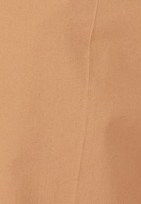 Tela de algodón en un suave color durazno, con una textura lisa y arrugas sutiles, además de un patrón sólido y uniforme.