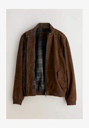 Brūns zamšādas žakete ar rāvējslēdzēja aizdari, ribainām aprocēm un pleda oderējumu. Aprīkots ar sānu kabatām un minimālu apkakles dizainu.