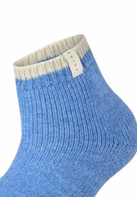 Blauer gerippter Socken mit einem cremefarbenen Bund und einem Etikett. Der Stoff wirkt strukturiert und bietet einen kontrastreichen Look zum glatten Bund.