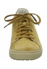 Sneaker in suede giallo senape con punta rotonda, lacci piatti e una sfumatura dorata testurizzata. Presenta una suola in gomma beige con dettagli di cucitura.