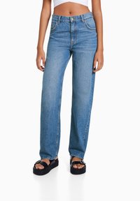 Jeans in denim blu a vita alta con gamba dritta, dotati di cinque tasche, passanti per la cintura e cuciture a contrasto. Texture liscia.