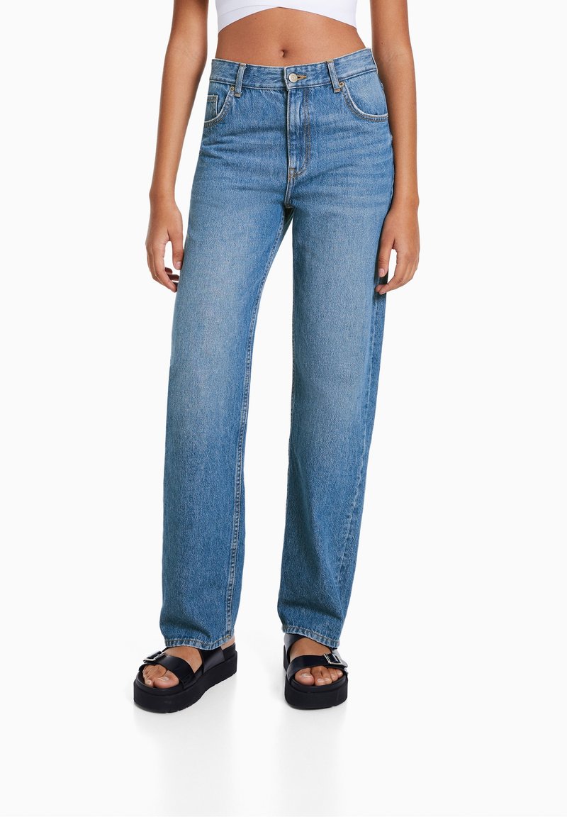 Jeans in denim blu a vita alta con gamba dritta, dotati di cinque tasche, passanti per la cintura e cuciture a contrasto. Texture liscia.