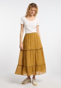 Gonna midi a più livelli di colore giallo senape con un motivo floreale. Realizzata in tessuto leggero, presenta una comoda vita elastica.