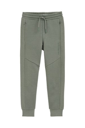 Žalios sportinės kelnės, pagamintos iš minkštos med�žiagos, su rūdžių formos rankogaliais, elastingu juosmeniu ir įstrižais tekstūruotais akcentais šoninėse dalyse.