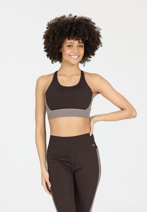 Bruine sportieve crop top met lichtgrijze accenten, met een racerback ontwerp. Hoge taille bruine legging met bijpassende zijaccenten.