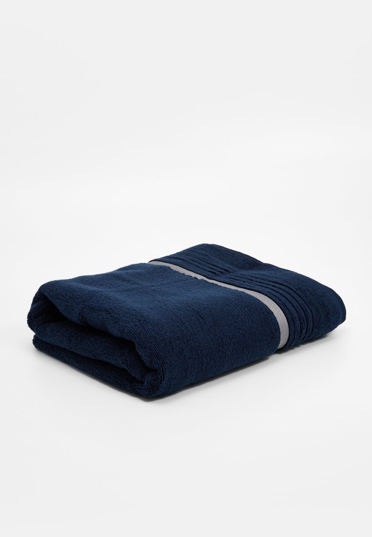 Serviette bleu marine, texture en velours, pliée avec deux bandes grises horizontales. Forme rectangulaire avec une finition en tissu doux et absorbant.