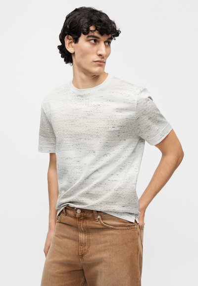 Ανοιχτό γκρι κοντομάνικη μπλούζα με υφή κυματιστού μοτίβου. Στρογγυλή λαιμόκοψη και διακριτικό λογότυπο στο μπροστινό μέρος. Συνδυάζεται με μπεζ παντελόνι.