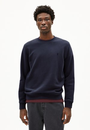 Marineblaue Sweatshirt aus Baumwollmischung, mit Rundhalsausschnitt, ausgestattet mit einem kleinen Logodetail auf der Brust, kombiniert mit einem bordeauxroten Hemd darunter.