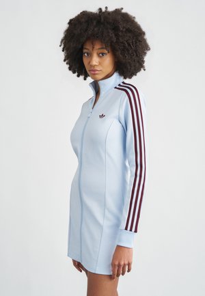 Hellblaues Kleid mit Reißverschluss aus glattem Stoff, mit dunkelroten Drei-Streifen-Akzenten an den Ärmeln und einem kleinen gestickten Logo auf der Brust.