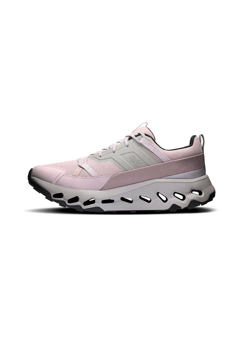 Chaussure de sport rose clair avec tige en mesh, accents gris, semelle intermédiaire blanche épaisse dotée de trous de ventilation et semelle extérieure en caoutchouc noir.
