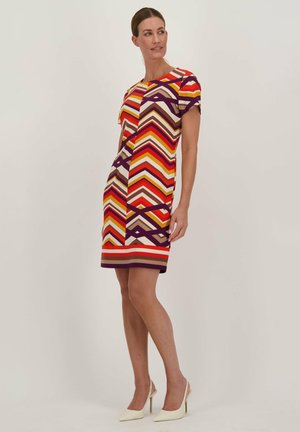 Multicolore zigzagpatroon jurk met korte mouwen, met warme tinten van rood, oranje en paars. Gemaakt van rekbaar materiaal, tot de knie.