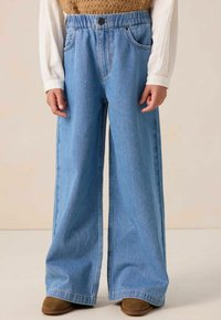 Jean large bleu clair à taille haute, avec une fermeture à bouton, des poches avant et une texture denim lisse.