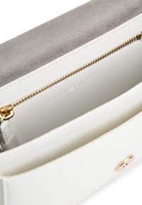Λευκή δερμάτινη τσάντα με γκρι φλαπά από σουέτ, λεπτομέρειες με χρυστό φερμουάρ και εσωτερικό διαμέρισμα. Διαθέτει κούμπωμα με κουμπί πατιλέτα.