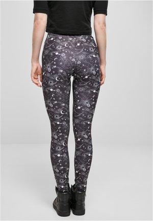 Leggings negre cu imprimeu cosmic, decorat cu stele, planete și lunii albe. Materialul este neted și are un design ajustat.