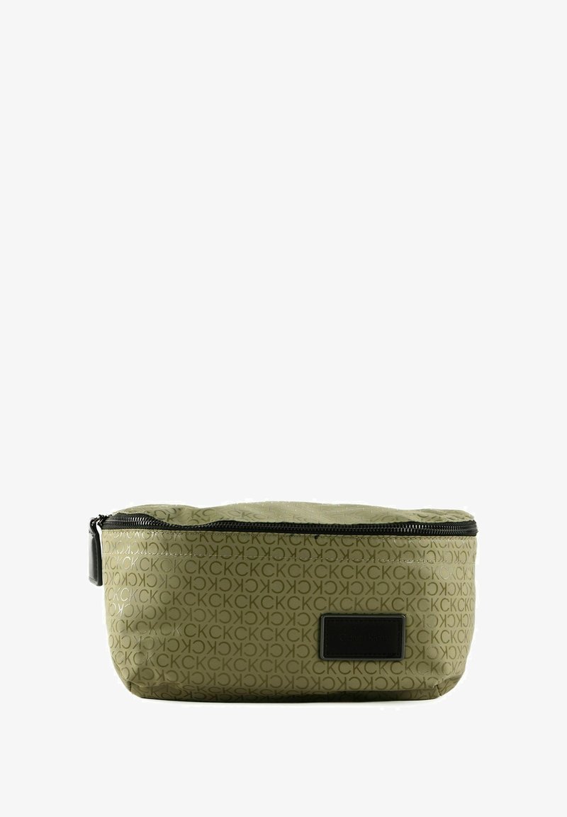 Trousse de maquillage vert olive avec motif répété du logo "CK", fermeture éclair et étiquette rectangulaire noire à l'avant. Matériau lisse et durable.