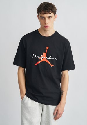 Black cotton t-shirt featuring a red “Jumpman” logo and white “Air Jordan” text on the front. Relaxed fit, crew neckline.
