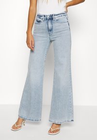 High-waisted light blue denim flared jeans with two front pockets and a button closure. Smooth texture with a slightly faded finish.