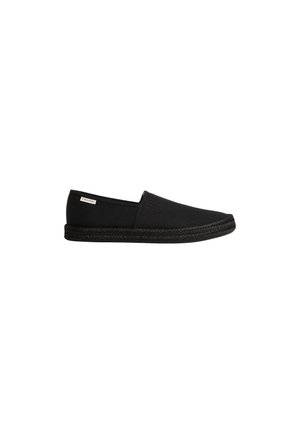 Zapato negro tipo espadrille sin cordones, con suela de yute trenzado y pequeña etiqueta de Calvin Klein en el lado cerca del talón.